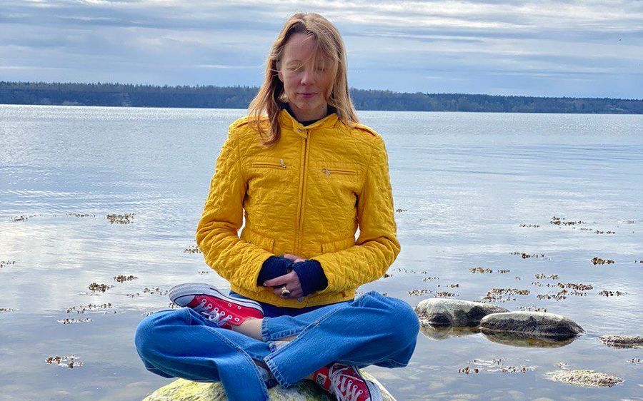 Irina Varlamova meditating on a stone by the water