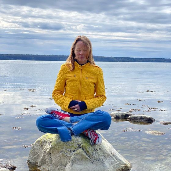 Irina Varlamova meditating on a stone by the water